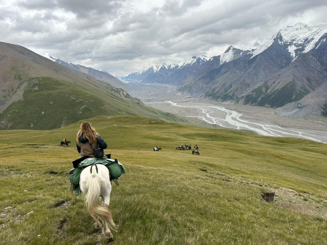 Rider overlooking a glacial valley with snow peaks